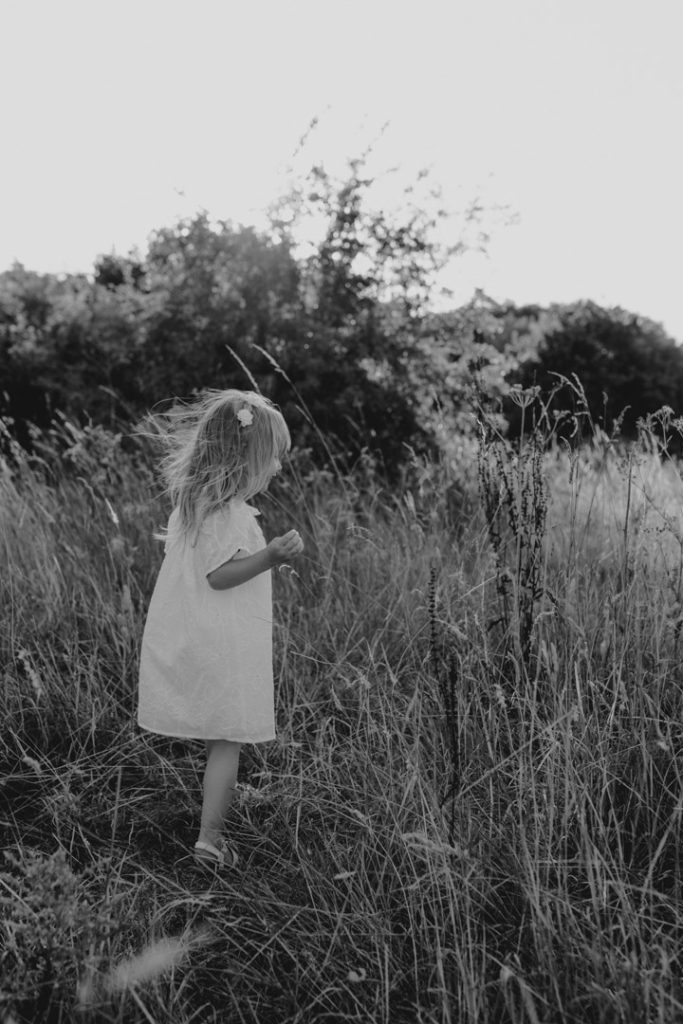 black and white image of a child in the long wild grass. Hampshire family photographer. Ewa Jones Photography