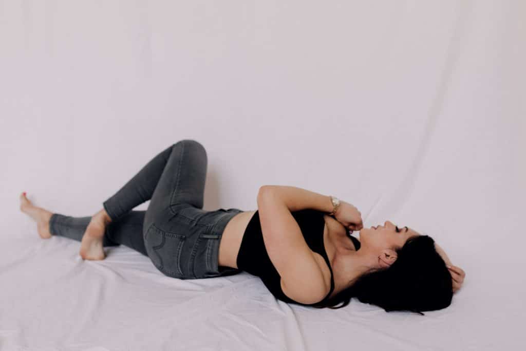 Model photo session. Model is laying on the bed sheet and hugging herself. Basingstoke model photographer. Hampshire photographer. Ewa Jones Photography