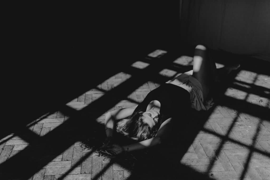 Woman is laying on the floor and the sun beams are on her body. Lovely black and white image. Female empowerment. Female photographer in Basingstoke. Ewa Jones Photography