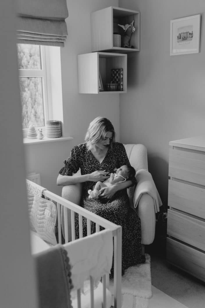 Mum is holding her newborn baby girl is sitting on the chair. natural lifestyle newborn photo session. Newborn photo session in Hampshire. Ewa Jones Photography