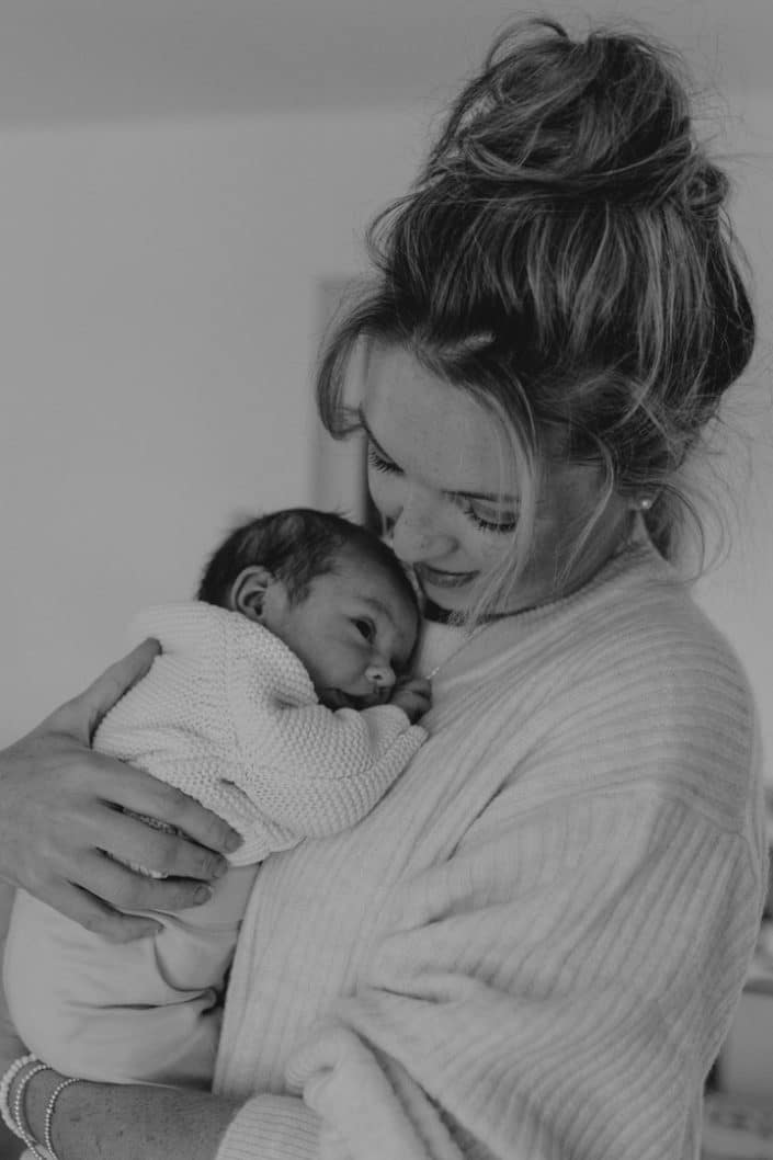 Mum is holding her newborn baby girl close to her and looking down on her. Newborn photoshoot in Hampshire. Newborn photographer Hampshire. Ewa Jones Photography