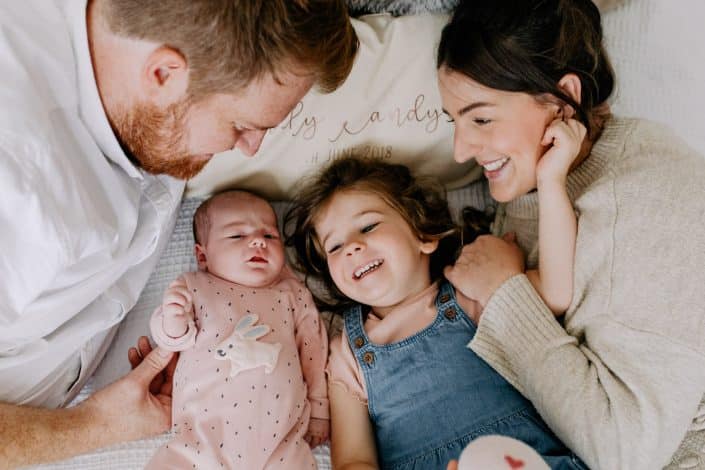 Natural lifestyle newborn photography. family is laying on the bed and smiling. Newborn photo shoot in Hampshire. Hampshire photographer. Ewa Jones Photography