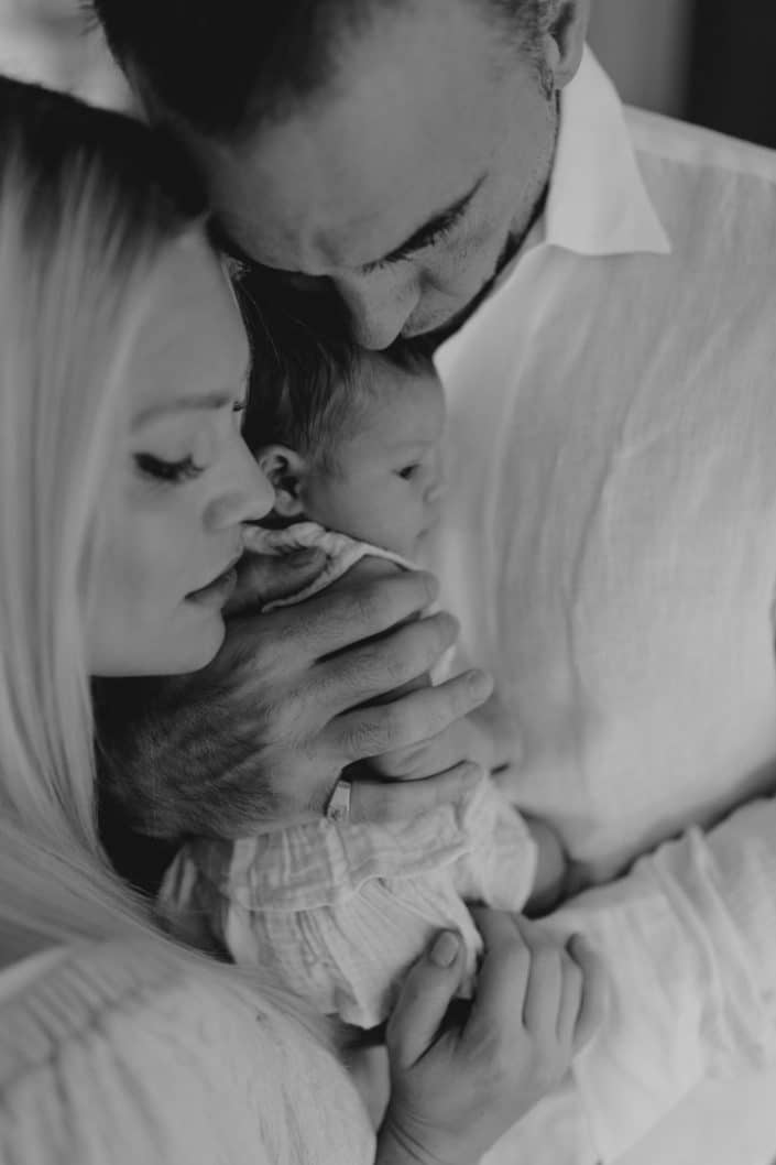 Black and white image of family cuddling together. Baby girl is in dads arms. Newborn photo session in London. Newborn photographer in Hampshire. Ewa Jones Photography