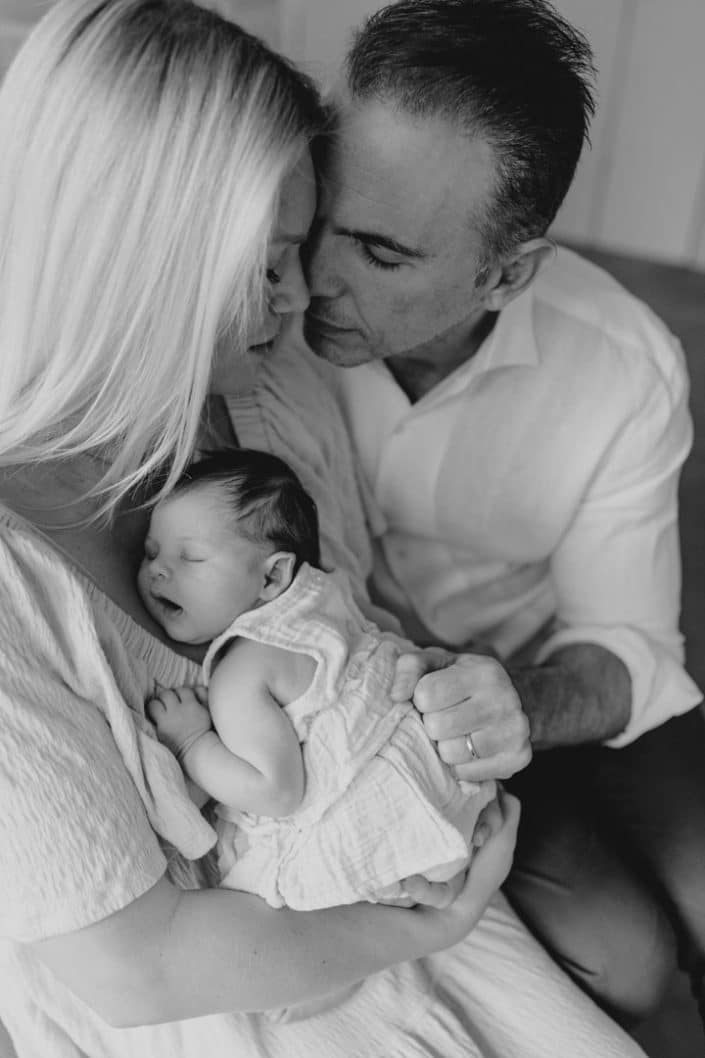 Parents are cuddling close. Baby girl is sleeping on mummy chest. Lovely intimate natural newborn photo session. Newborn photography in Hampshire. Ewa Jones Photography