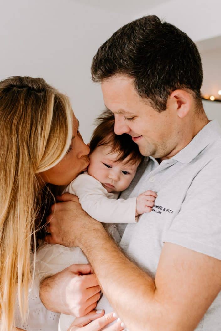 Close up of mum and dad cuddling newborn baby girl and mum is kissing her. Newborn photo session in Hampshire. Basingstoke photographer. Ewa Jones Photography