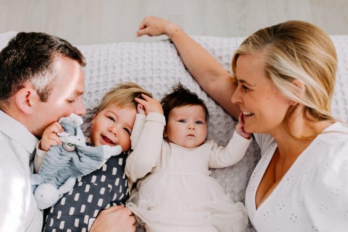 Family of four is laying on bed and cuddling. candid newborn photo shoot at home. Hampshire newborn photographer. Ewa Jones Photography