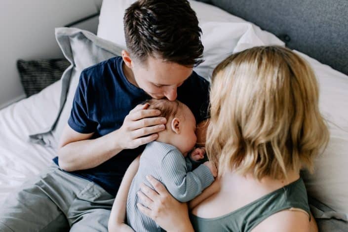 Mum and dad are cuddling close their newborn baby boy. Baby boy is sleeping. Newborn photo shoot in Hampshire. Hampshire newborn photographer. Ewa Jones Photography