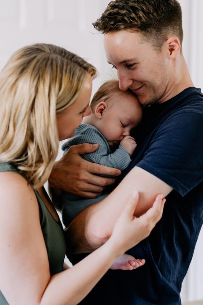 mum and dad are cuddling to newborn baby boy. Baby boy is sleeping on daddy. Lifestyle newborn photo session. Newborn baby photographer Hampshire. Ewa Jones Photography