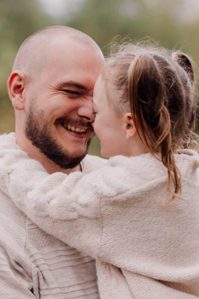 Dad is cuddling his daughter and holding her close to him. Autumn family photo session. Natural family photo session in Hampshire. Hampshire photographer. Ewa Jones Photography