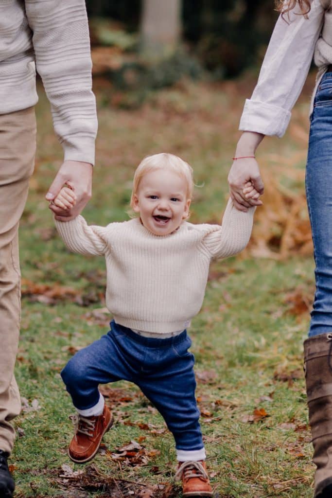 Little boy is walking and mum and dad are holding his hands. Family photo session in the autumn. Family photographer in Basingstoke. Hampshire family photographer. Ewa Jones Photography