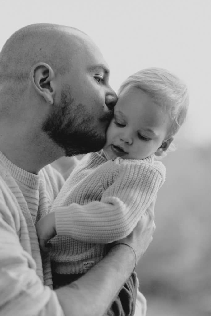 Dad is kissing his baby boy in his cheek. family photo session in the autumn. Hampshire photographer. Ewa Jones Photography