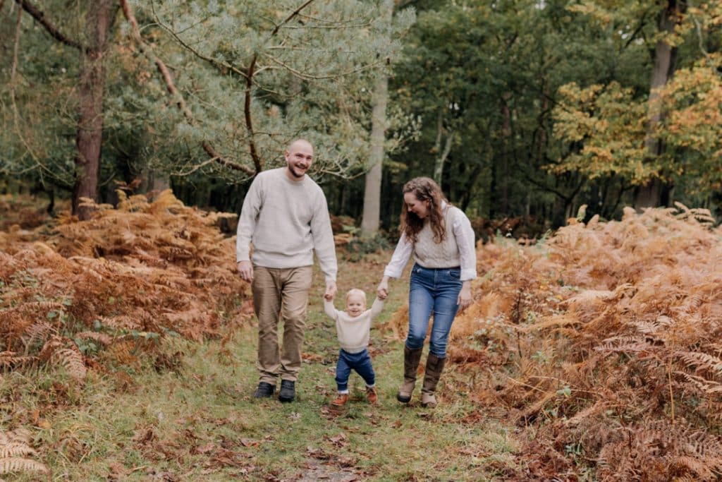 Little boy is walking and mum and dad are holding his hands. Family photo session in the autumn. Family photographer in Basingstoke. Hampshire family photographer. Ewa Jones Photography