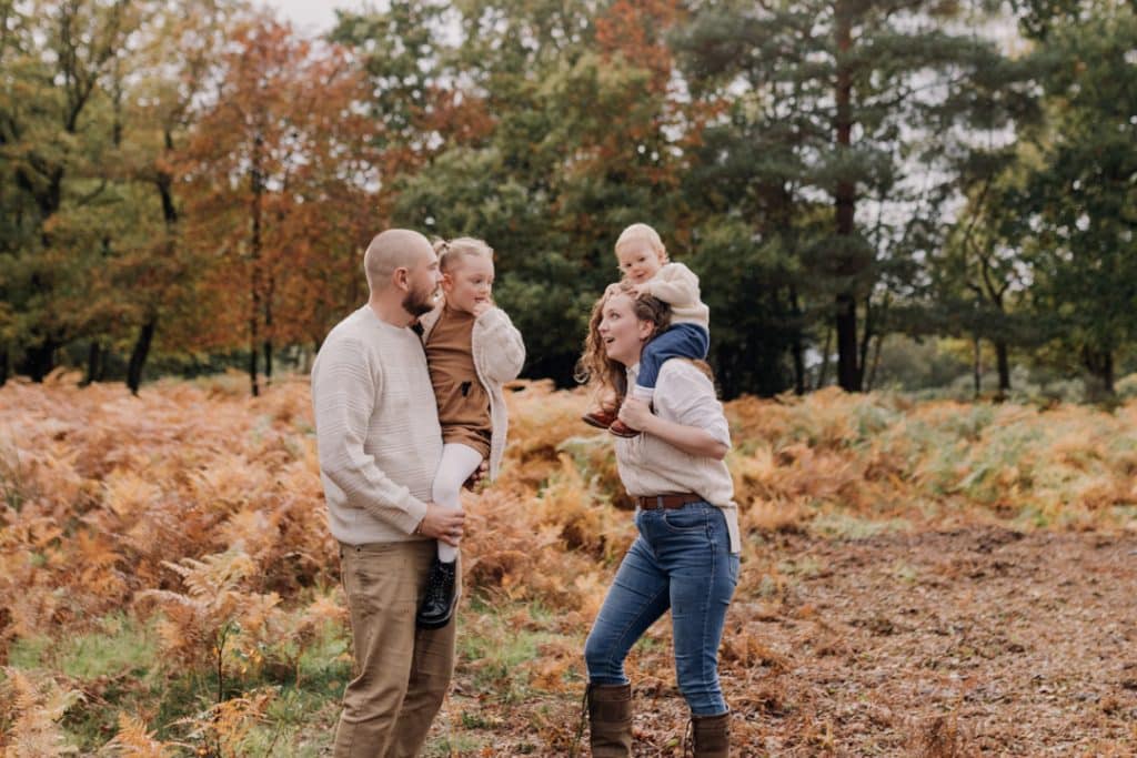 family of four is in the autumn leaves. the are looking at each other. family photo shoot in autumn. Hampshire family photographer. Ewa Jones Photography