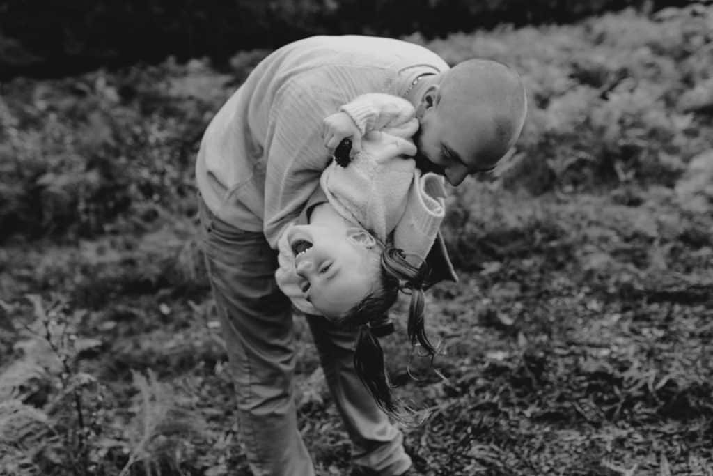 Dad is tickling his girl and she is laughing. Lifestyle family photo session. Basingstoke family photographer. Hampshire photographer. Ewa Jones Photography