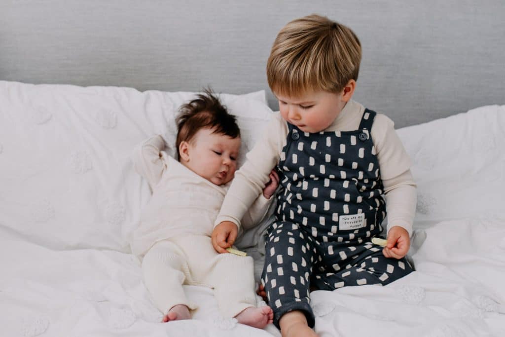 brother and sister are sitting on the bed. Hampshire newborn photo shoot. Ewa Jones Photography