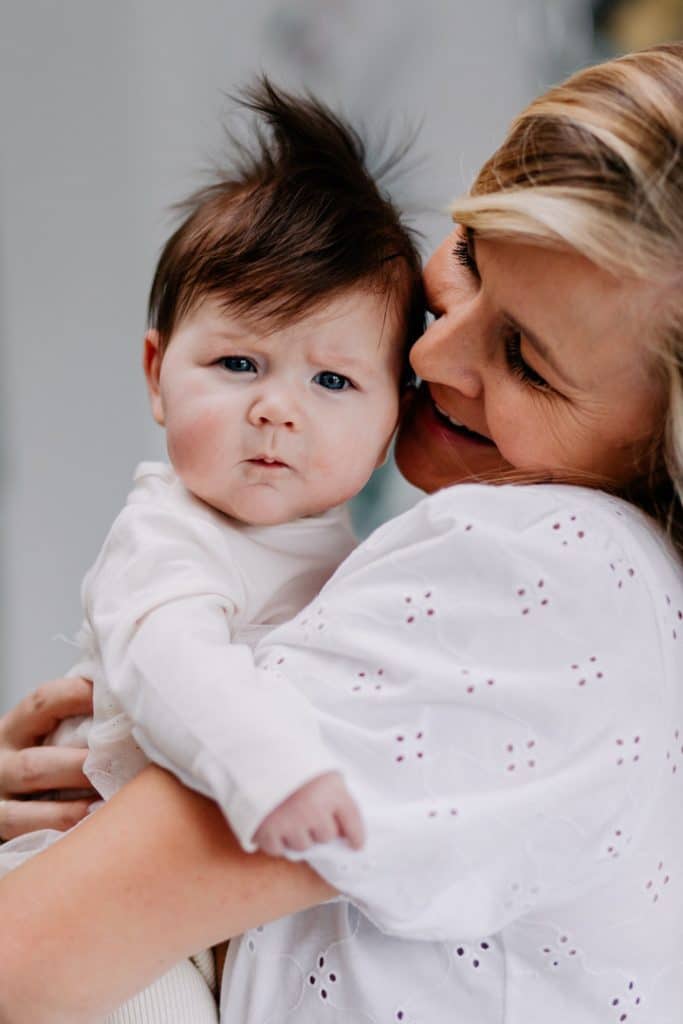 mum is holding close her newborn baby girl. newborn photo shoot at home. Lifestyle Hampshire newborn photography. Ewa Jones Photography.