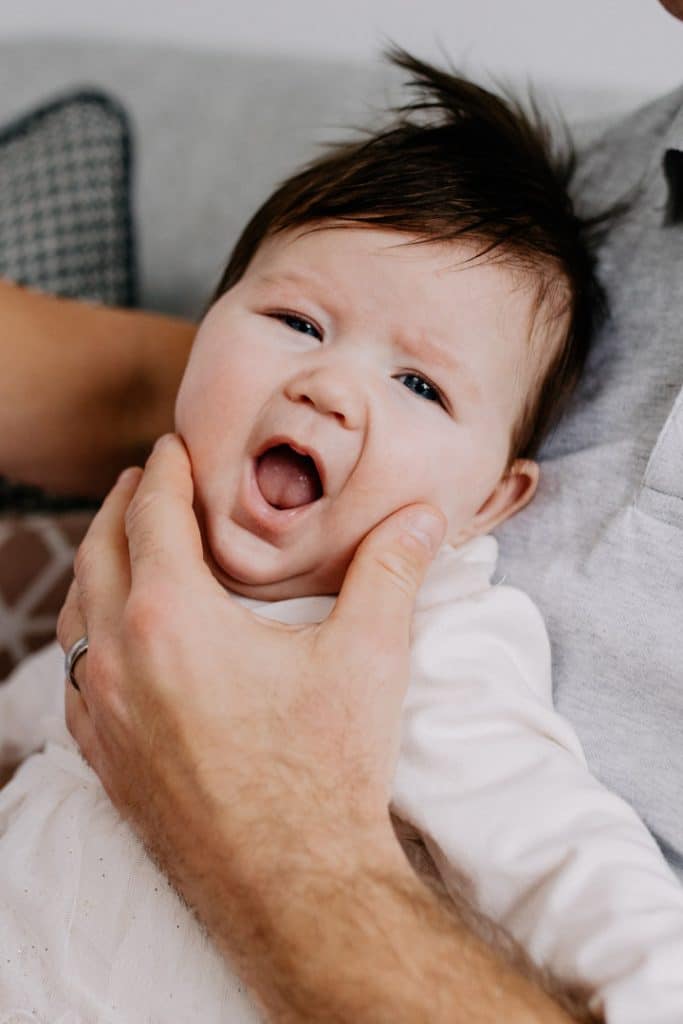 Close up of newborn baby girl looking at the camera and smiling. Hampshire newborn photographer. Basingstoke family photographer. Ewa Jones Photography.