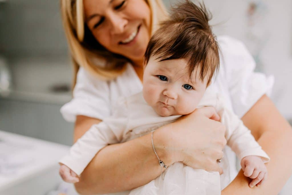 Mum is cuddling her baby daughter and looking at her. Hampshire newborn photo shoot at home. Home and lifestyle newborn photo sessions. Ewa Jones Photography.