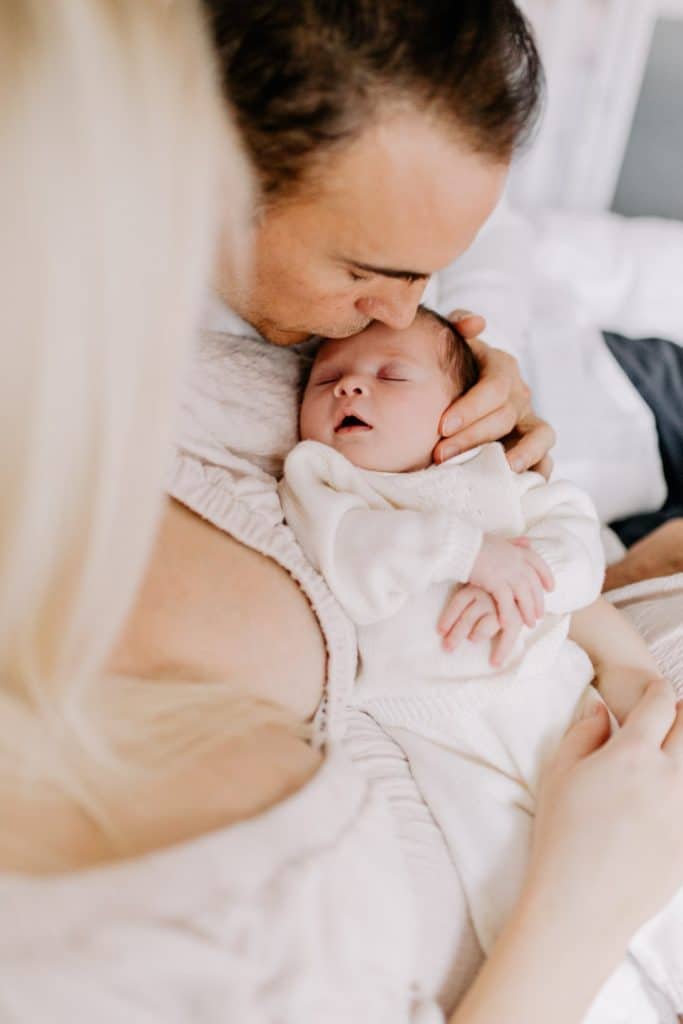 Newborn photo shoot in London-14 Dad is kissing newborn girl. Newborn baby girl is sleeping. Basingstoke newborn baby photo shoot. Hampshire photographer. Ewa Jones Photography