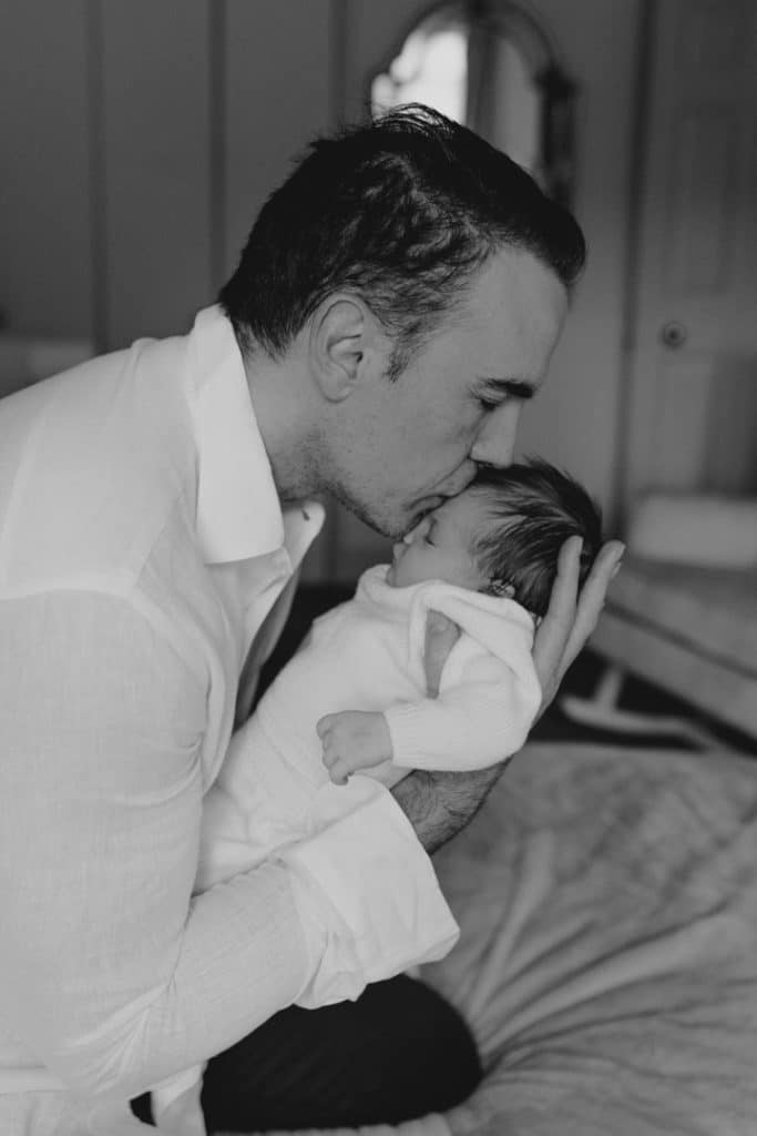 Newborn photo shoot in London-15 Dad is kissing his newborn baby girl on her forehead. London newborn photographer. Hampshire newborn photographer. Ewa Jones Photography