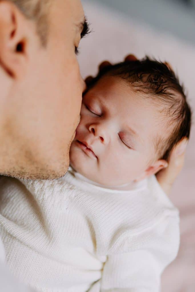 Newborn photo shoot in London-16 Dad is kissing his newborn baby girl on her forehead. London newborn photographer. Hampshire newborn photographer. Ewa Jones Photography
