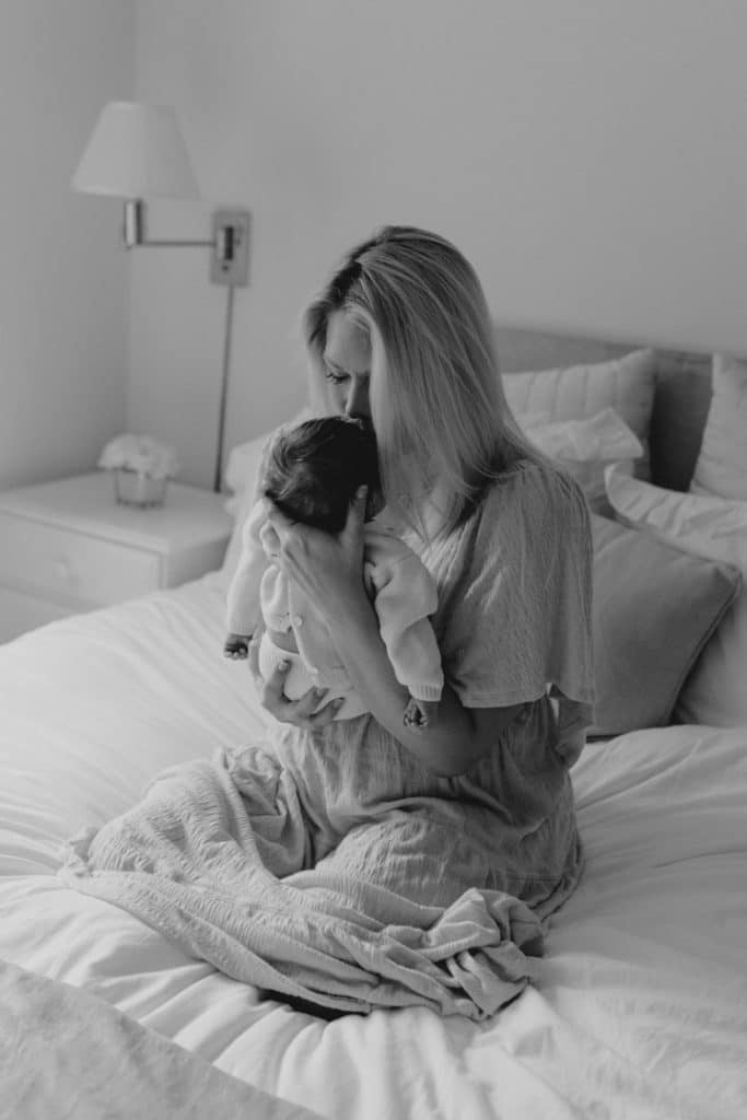 Newborn photo shoot in London-19 Mum is kissing her newborn baby girl and sitting on the bed. London newborn baby photo session. Hampshire newborn photographer. Basingstoke newborn baby photo shoot. Ewa Jones Photography