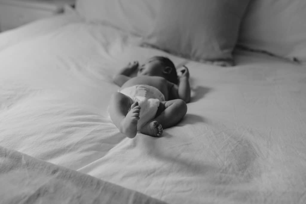 Newborn photo shoot in London-2 Newborn baby is laying on the bed and looking out. Newborn photoshoot in London. Hampshire photographer in London. Ewa Jones Photography