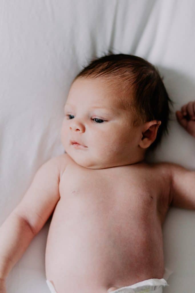 Newborn photo shoot in London-3 Close up of newborn baby girl laying on the bed and looking away. Lifestyle natural baby photo session in London. Basingstoke photographer in London. Ewa Jones Photography