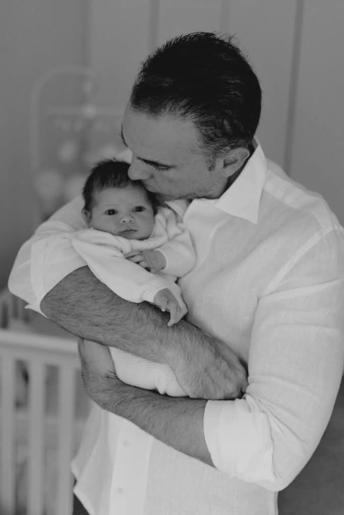 Newborn photo shoot in London-4 Dad is cuddling his newborn baby girl. Lovely candid black and white newborn photo session. Hampshire newborn photographer in London. Ewa Jones Photography