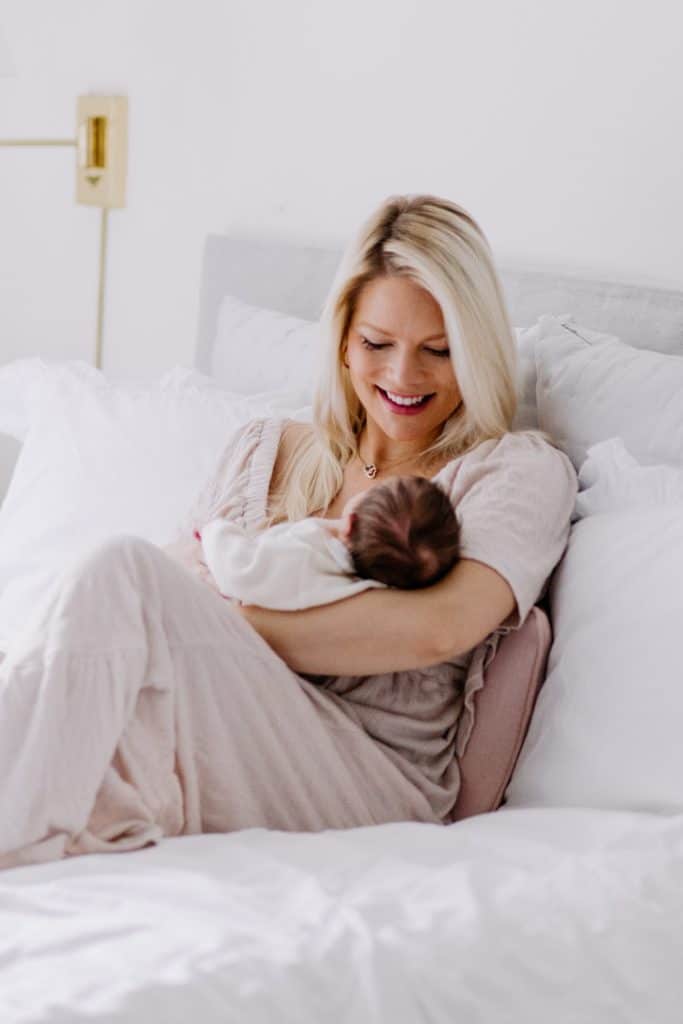 Newborn photo shoot in London-9 Mum is cuddling her baby girl and sitting on the bed. Mum is wearing lovely dress. Newborn photo session in London. Hampshire newborn photographer. Ewa Jones Photography