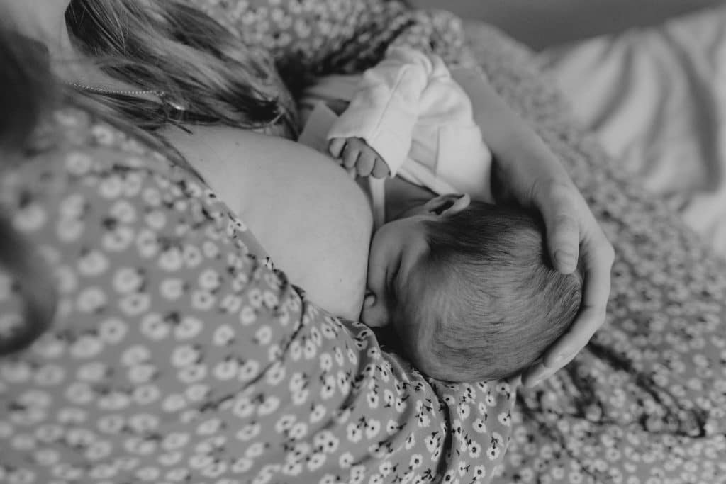Mum is breastfeeding her newborn baby girl. Natural unposed newborn photo session in Hampshire. Ewa Jones Photography