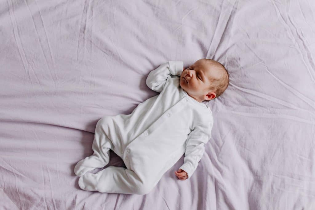 newborn baby girl is sleeping on bed. Newborn photography in Basingstoke - first days. Hampshire newborn photo shoot. Ewa Jones Photography