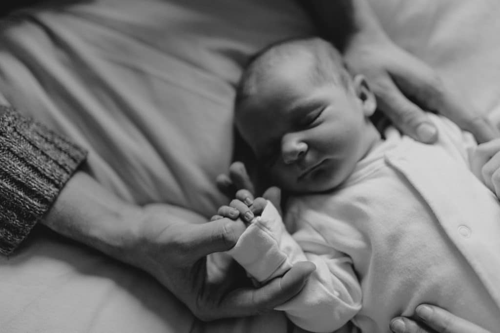 Close up of dad is holding his newborn baby girl hand. natural newborn photo session in Hampshire. Ewa Jones Photography