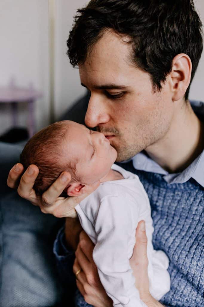 Dad is kissing his newborn baby girl. in home newborn baby photo shoot. Ewa Jones Photography