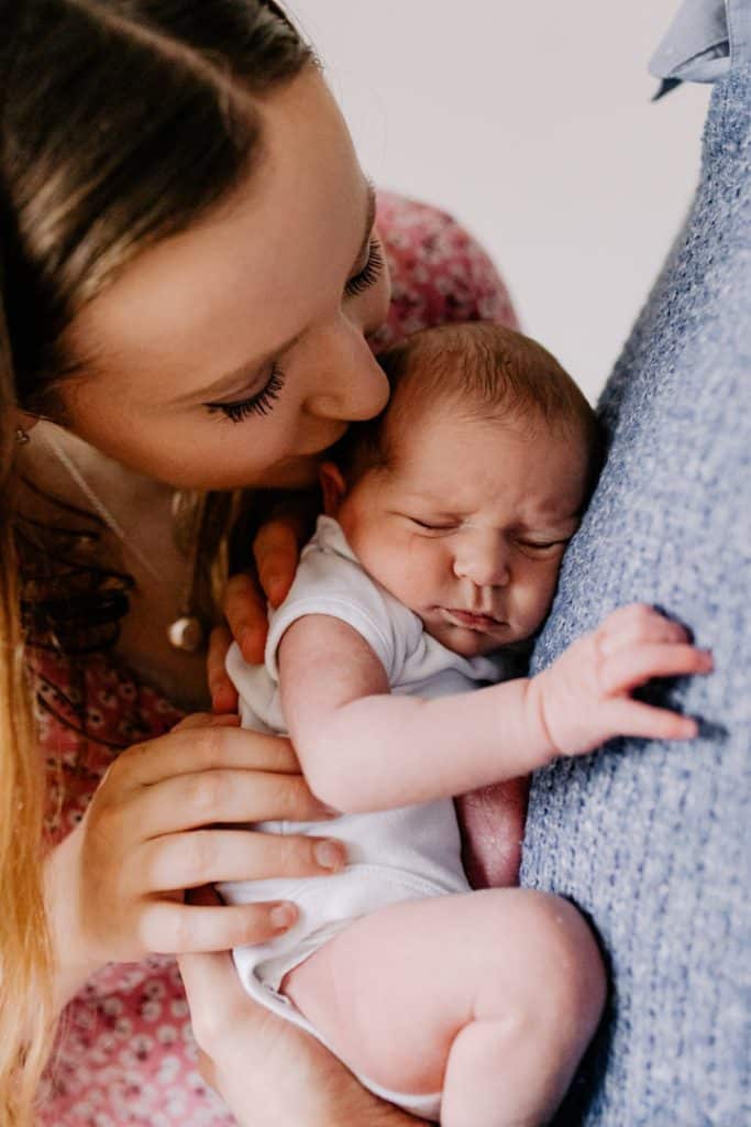 Mum is kissing her newborn baby girl on top of hear head. Newborn photo shoot at home. Hampshire newborn photo session. Hampshire photographer. Ewa Jones Photography