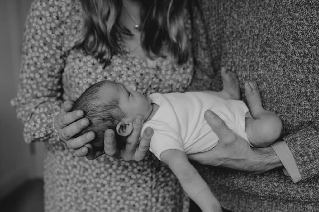 mum and dad are holding newborn baby girl. newborn photo shoot. Black and white newborn images. Hampshire photo session. Ewa Jones Photography