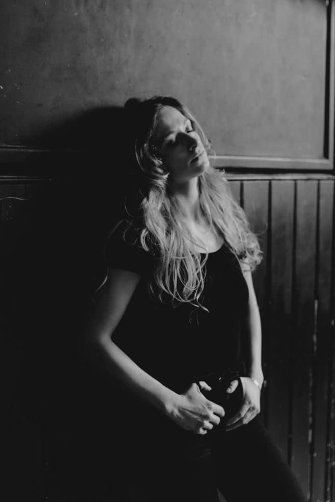 Empowering female sessions-10 Female is standing against black wall. She has her eyes closed. Female photography. Hampshire models. Hampshire photo shoot. Ewa Jones Photography