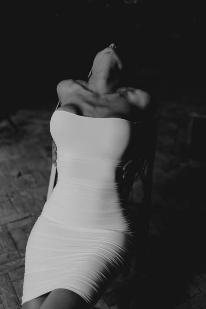 Female is laying on the chair and wearing white dress. Boudoir intimate female photo sessions in Basingstoke Hampshire. Ewa Jones Photography