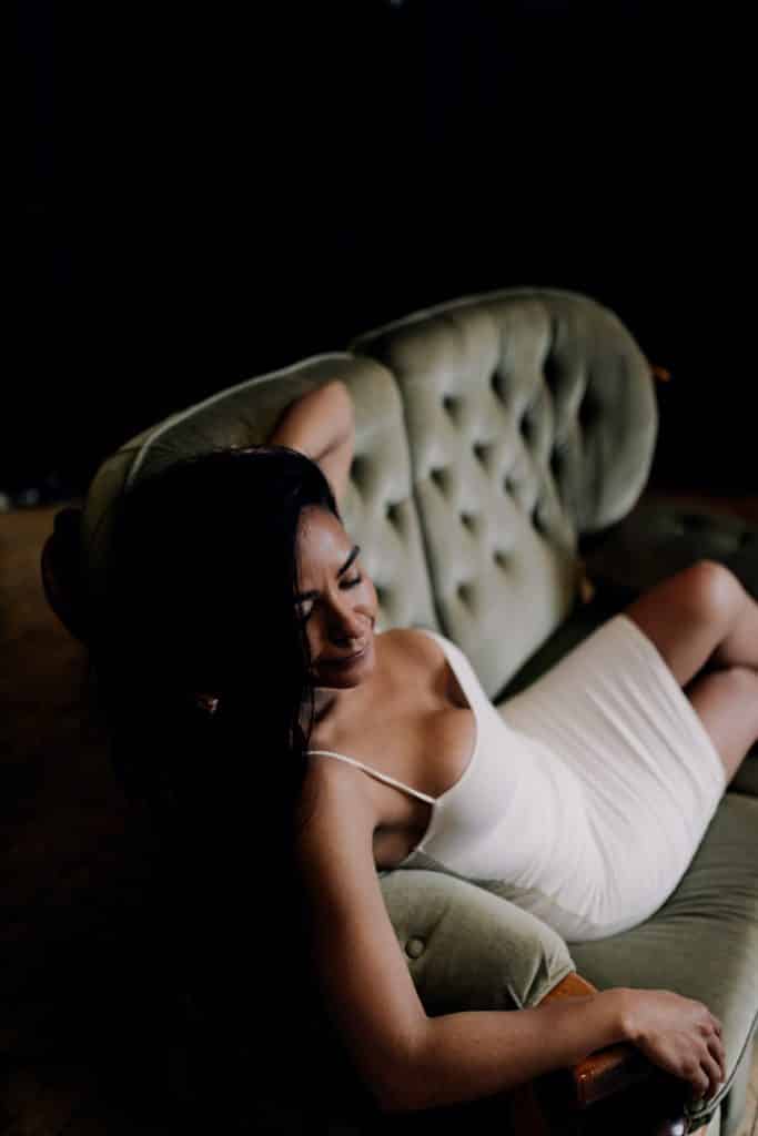 Female is sitting on the sofa and looking down Boudoir female sessions in Hampshire. Ewa Jones Photography