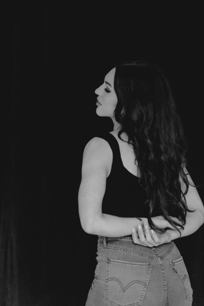 Female is standing turned to the lens. she is wearing black top and jeans. Female photo shoot in Basingstoke. Ewa Jones Photography