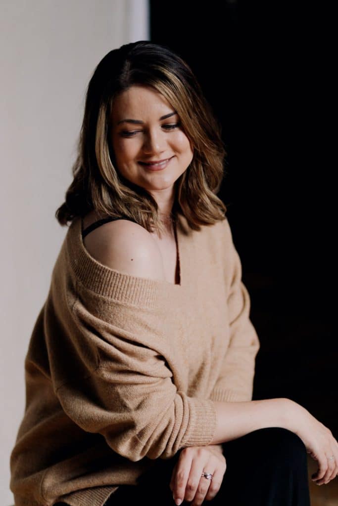 Woman is wearing nice jumper and looking down over her shoulder. Female photo sessions. Studio female photography. Basingstoke photographer. Ewa Jones Photography