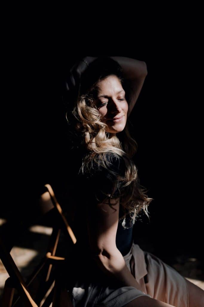 Empowering female sessions-8 Female is sitting on the chair and looking at the lens. She is wearing black top and wide trousers. Female photo shoot in Basingstoke. Hampshire photographer. Ewa Jones Photography