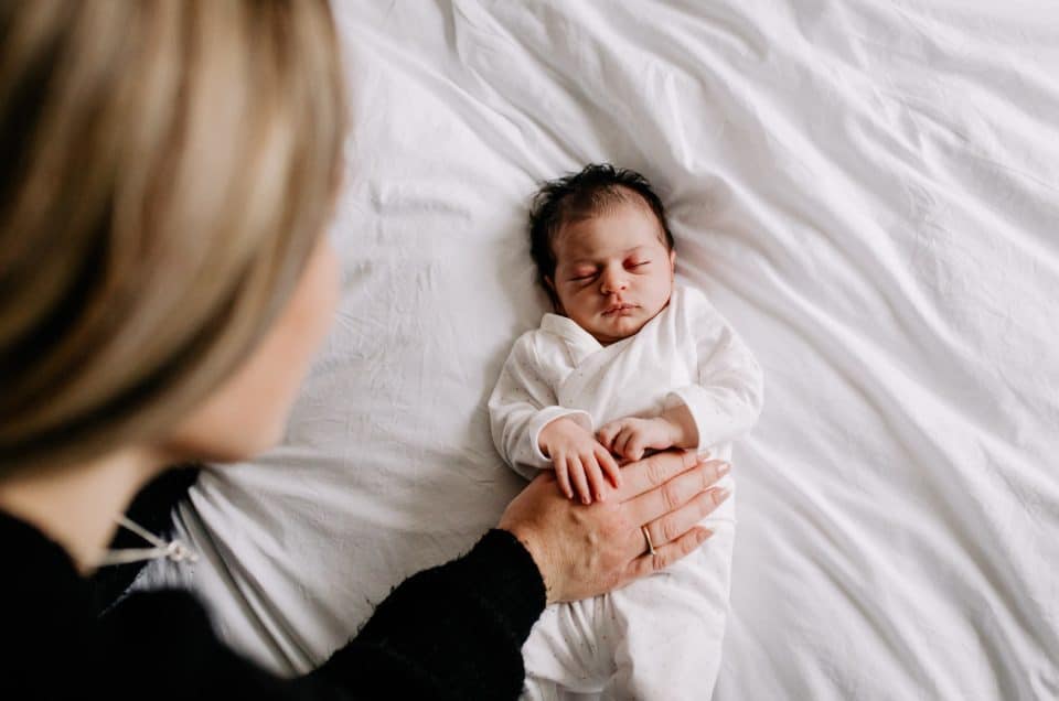 mum is looking down at her newborn baby girl. newborn baby girl is sleeping. Candid moment between mother and a baby. Ewa Jones Photography. Capture Love: Insights into a Newborn Photo Shoot with Mum