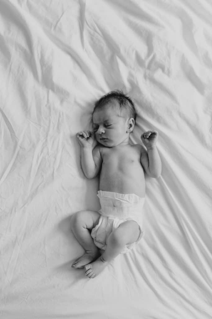newborn baby girl is laying on bed sleeping. Hampshire newborn photographer. Ewa Jones Photography