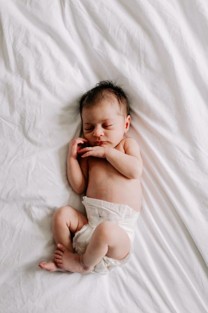 newborn baby girl is laying on bed sleeping. Hampshire newborn photographer. Ewa Jones Photography