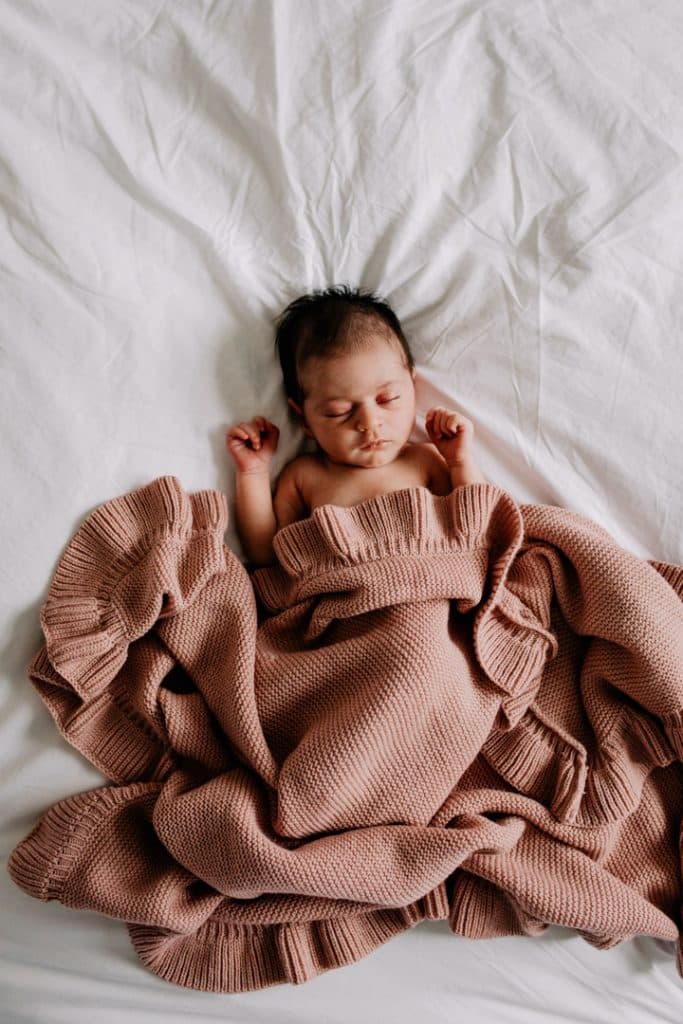newborn baby is laying on bed and sleeping. she is covered with a blanket. Basingstoke photographer. Ewa Jones Photography