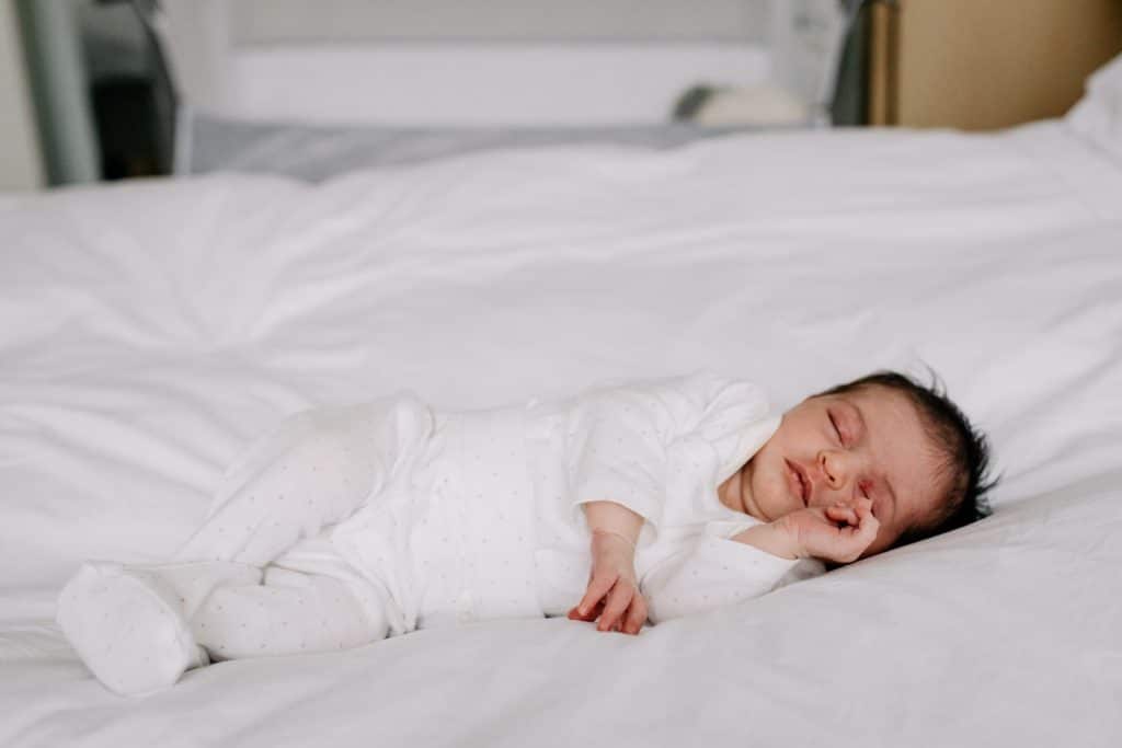 Baby is sleeping on the bed. Newborn photography in Hampshire. Ewa Jones Photography