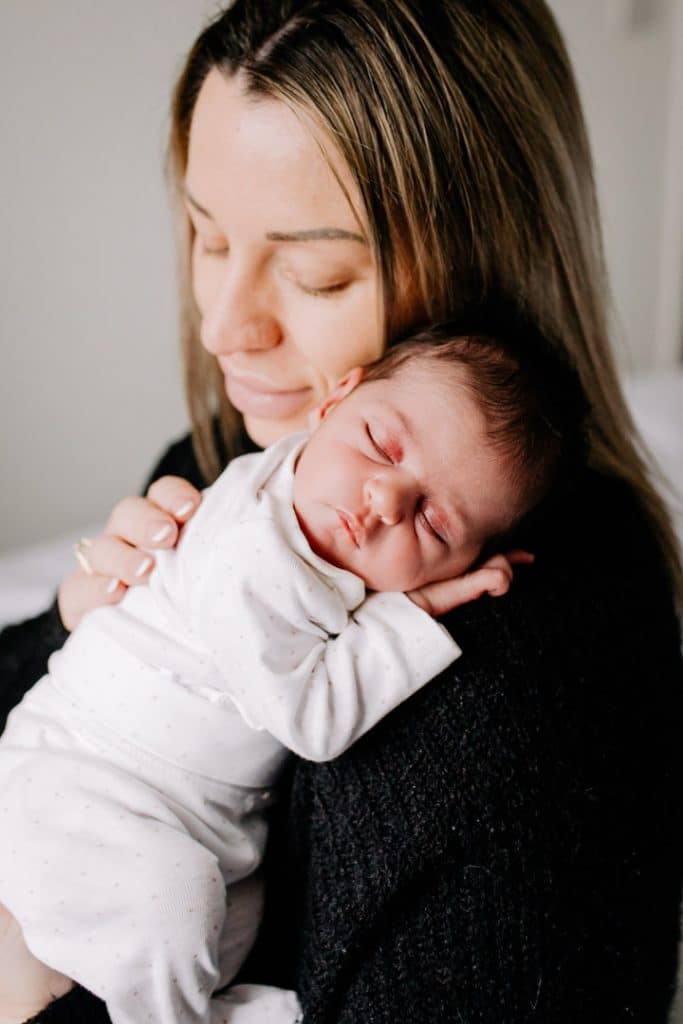 Newborn baby girl is resting on mummy's shoulder and sleeping. Natural in home newborn photo sessions. Hampshire photographer. Ewa Jones Photography