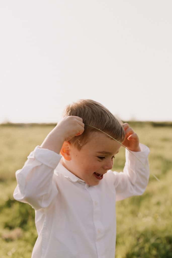 Claudia and Lorenzo-11 boy is looking down and happy in the field. family photo session in spring time. spring photo shoot. Hampshire photo session. Hampshire photographer. Ewa Jones Photography
