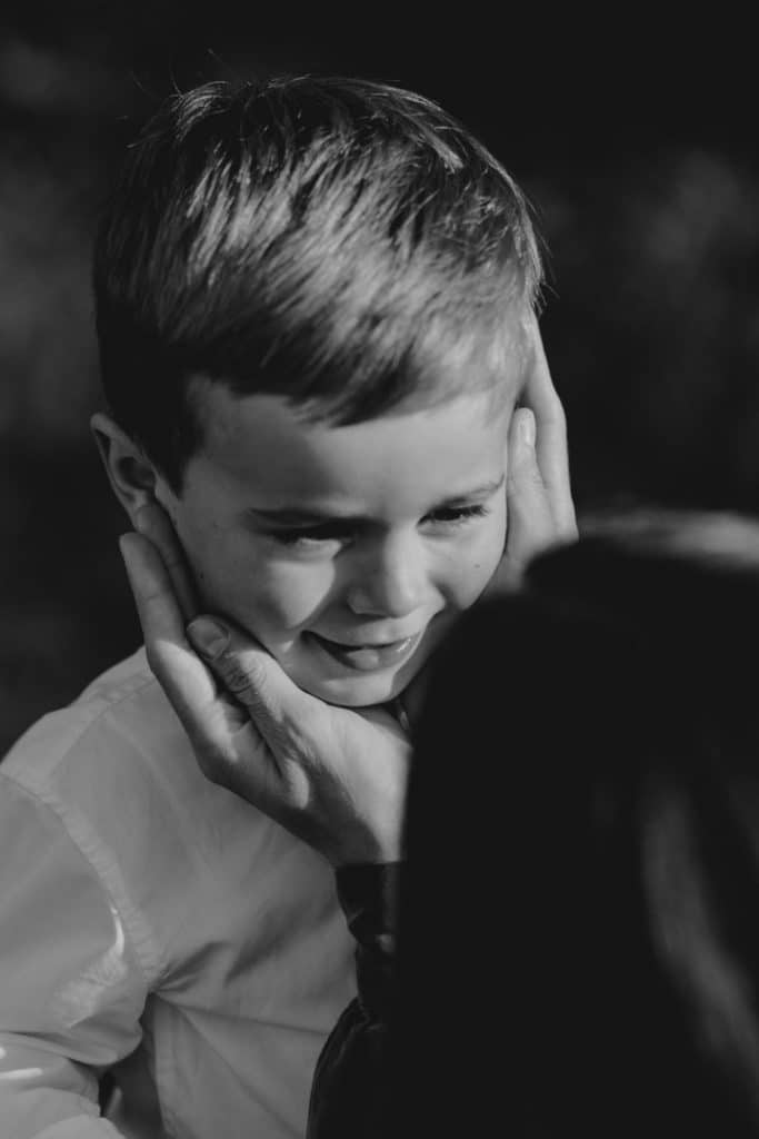 Claudia and Lorenzo-2 Mum is holding her hands on her little boy. Little boy is looking at his mum. Candid family photo session in Hampshire. Hampshire family photographer. Ewa Jones Photography